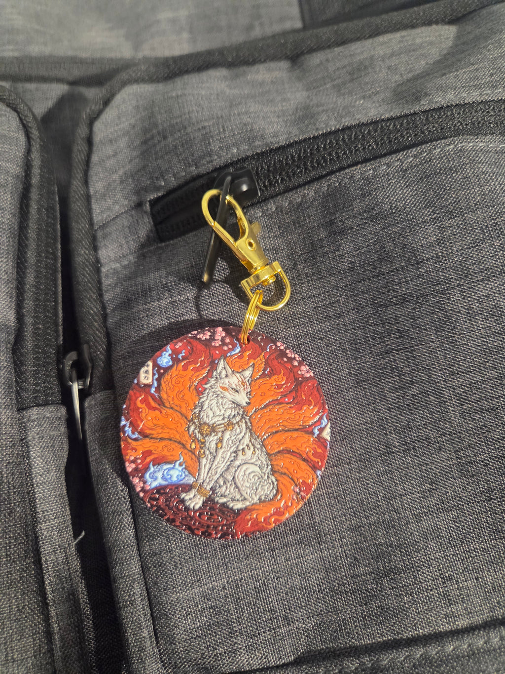 Close-up of nine-tailed fox keychain with gold-tone clip and orange tails