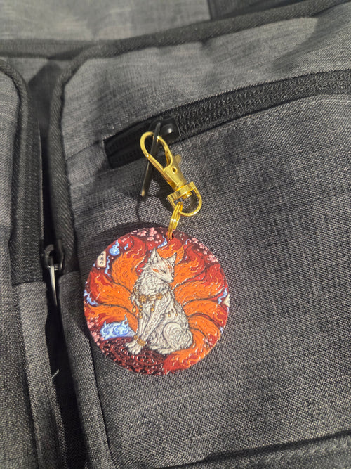Close-up of nine-tailed fox keychain with gold-tone clip and orange tails